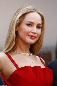 a woman in a red dress is smiling at the camera and wearing a diamond necklace