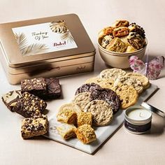 an assortment of cookies and other treats on a plate next to a tin of tea