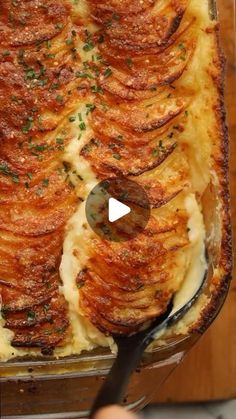 a casserole dish with potatoes and parmesan cheese is being prepared to be eaten