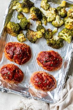 broccoli and other food items on tin foil lined up on a white surface