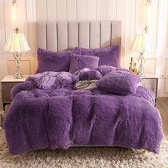 a bed covered in purple fluffy blankets and pillows