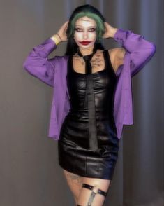 a woman with green hair wearing a purple shirt and black leather skirt is posing for the camera