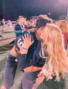 a man kissing a woman on the cheek at a football game