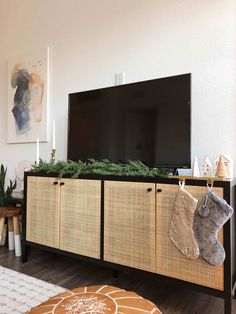 a flat screen tv sitting on top of a wooden entertainment center next to a christmas tree