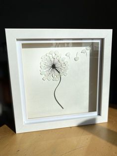 a white frame with a dandelion cut out of it's petals on a table