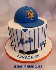 a cake with a baseball hat on top of it and the name mets written in fondant