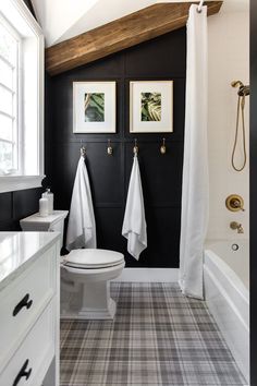 a bathroom with black and white walls, two pictures on the wall above the toilet