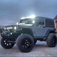 a jeep with lights on is parked in front of a brick building