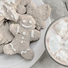 a plate full of cookies and marshmallows next to a glass of milk