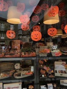 a store window with pumpkins and jack - o'- lanterns hanging from it