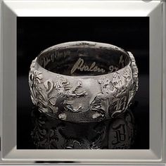 a silver ring with writing on it and an image of two people in the background