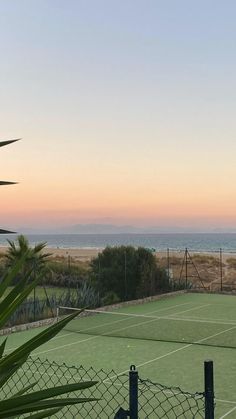 a tennis court with the ocean in the background