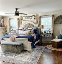 a bedroom with a large bed and lots of pillows on the headboard, along with two chairs