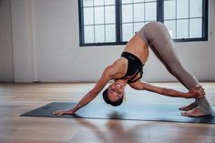 a woman is doing yoga on a mat in the middle of an open floored room