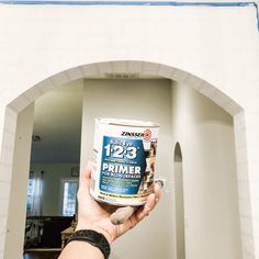 a person holding up a can of primer