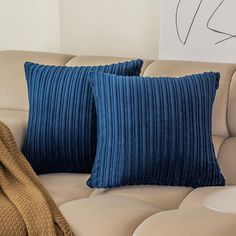 two blue pillows sitting on top of a couch