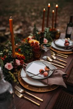 the table is set with plates, silverware and candles for an elegant fall wedding