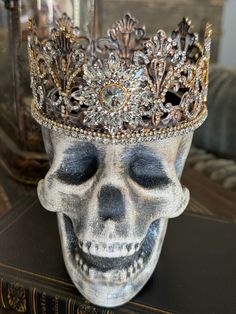 a skull with a crown on it's head sitting on top of a book