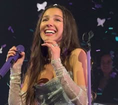 a woman holding a microphone in her right hand and confetti falling around her