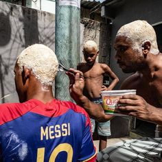 a man is shaving his face while two other men are standing around him and eating