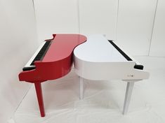 a red and white piano sitting next to each other on top of a white table