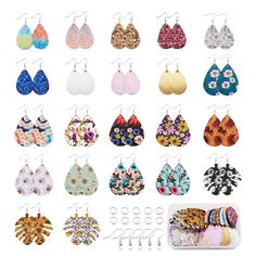 many pairs of earrings hanging from hooks on a white wall with flowers and leaves in them