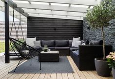 an outdoor living area with black furniture and potted plants