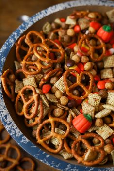 a bowl full of halloween snack mix with pretzels and candy cornflakes