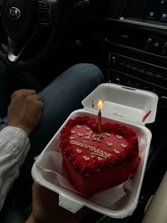 a heart shaped cake with a lit candle in the middle is being held by a man