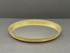 an oval gold tray with decorative designs on the rim and sides, sitting on a gray surface