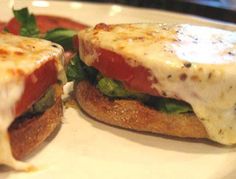 two sandwiches are sitting on a plate with cheese and tomato sauce in the middle one is cut in half