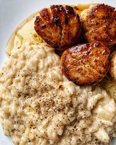 a white plate topped with macaroni and cheese covered in seared scallops