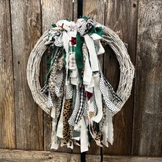 a wreath is hanging on the side of a wooden fence with leopard print scarves