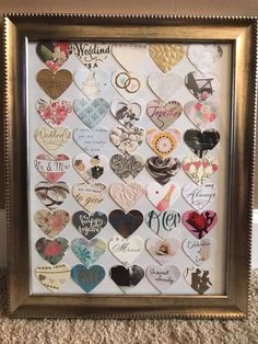 a gold frame filled with lots of different types of heart shaped magnets on the wall