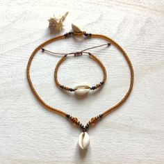 Jewelry made of natural cowrie shells (16 - 19 mm), honey / bronze color original Czech glass beads (3.1 / 4.1 / 5.6 mm Rocailles Preciosa) and waxed polyester cord (original Linhasita 1 mm). A necklace is available in 3 lengths (40 cm = 15.74 inches, 45 cm = 17.71 inches or 50 cm = 19.68 inches). The length of a bracelet is adjustable and should fit all wrists sizes.     The jewelry is robust and fully waterproof. If you have any questions/wishes, please don't hesitate to contact me! Adjustable Gold Beaded Shell Necklace, Bohemian Adjustable Gold Shell Necklace, Brown Beaded Shell-shaped Jewelry, Bohemian Gold Beaded Bracelets With Shell, Brown Beaded Shell Jewelry, Bohemian Gold Beaded Shell Bracelets, Bohemian Brown Shell Necklace With Round Beads, Gold Bohemian Shell For Festival, Gold Bohemian Strand Beaded Bracelets