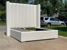 a white bed sitting in the middle of a sidewalk