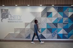 a woman walking in front of a wall that has the words unty health care on it