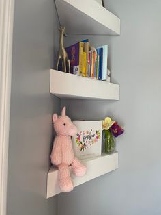 two white shelves holding books and stuffed animals