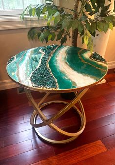 a green and white table sitting on top of a wooden floor next to a potted plant