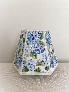 a blue and white lamp shade with flowers on it sitting on top of a table