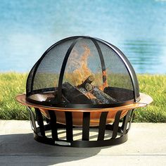 a fire pit sitting on top of a wooden table next to a body of water