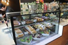 a display case filled with lots of different types of sandwiches and desserts on plates