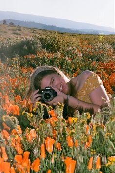 a woman taking a photo in a field of flowers with an old fashioned film camera