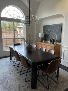 a dining room table and chairs in front of a large window with an arched doorway