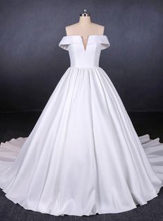 a white wedding dress on a mannequin with ruffled skirt and off the shoulder