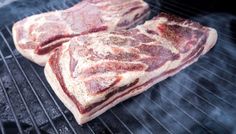 two steaks cooking on an outdoor grill