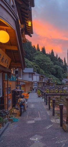 the sun is setting over an old town with many shops and restaurants on the street