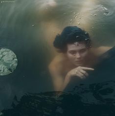 a woman is submerged in the water with her hand on her chin and looking at something