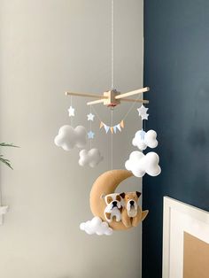 a baby crib mobile with two teddy bears hanging from it's sides and clouds in the background