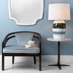 a chair and table with a lamp on it in front of a blue painted wall